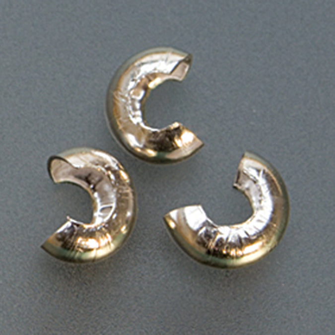 Close-up of three 3mm silver plated crimp covers for jewelry making