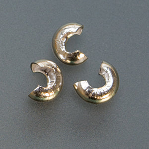 Close-up of three 4mm silver plated crimp covers used for jewelry making to conceal crimps and create a polished finish
