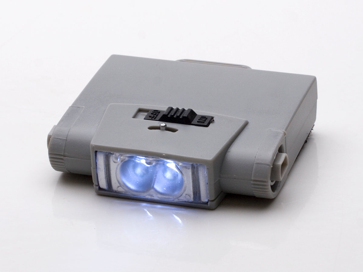 Compact gray headband magnifier light with bright white LED and on/off switch.