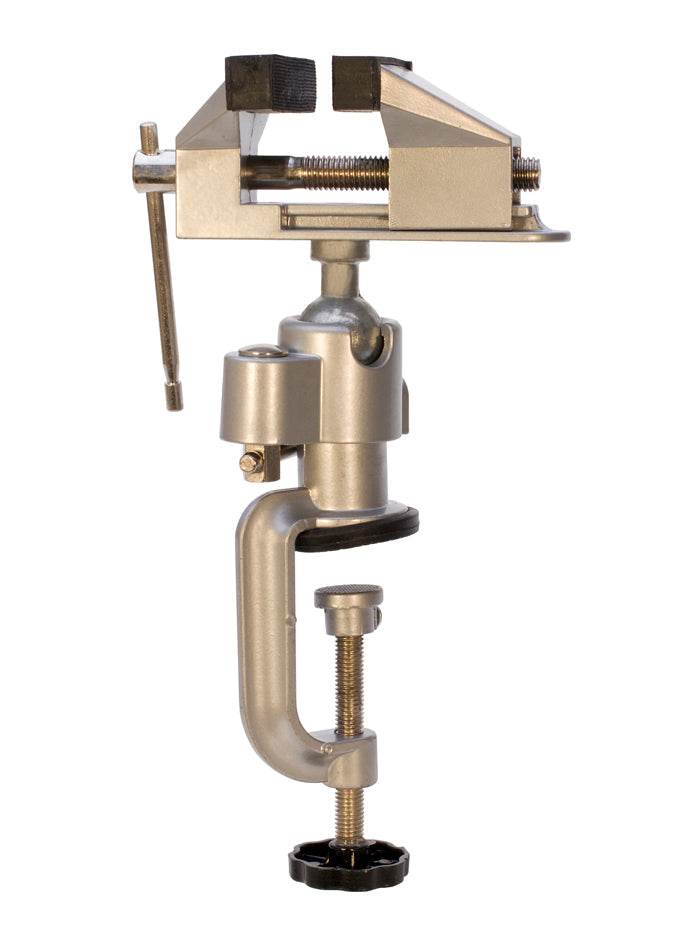 Tabletop vise with 3-inch rubber-lined jaws clamping a small metal piece on a workbench with 360-degree rotation and tilt features